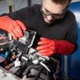Foto: ein Kfz Mechaniker tauscht Bauteil am Elektromotor aus